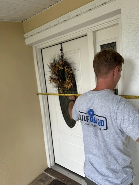 GulfGuard team member measuring a front-door opening for custom storm protection.