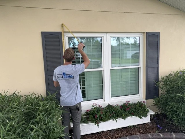 GulfGuard field measurement of a double window opening before custom hurricane fabric fabrication.